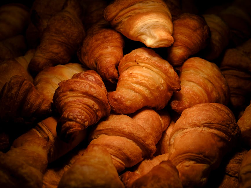 A mouth-watering close-up of golden, freshly baked croissants stacked together, tempting ready to eat.